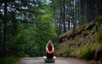 Woman practicing yoga in a tranquil forest setting, symbolizing peace and nature.