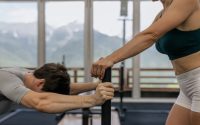 A couple working out together at an indoor gym with mountain views.